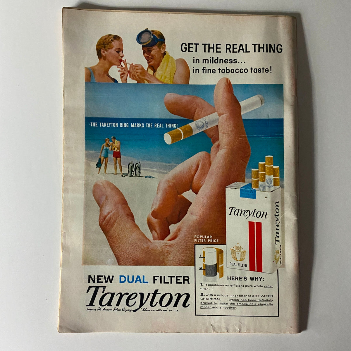 Cigarette advertisement for Tareyton, showcasing a beach scene with a man holding a cigarette, from a vintage magazine issue, emphasizing the product's mildness and taste.