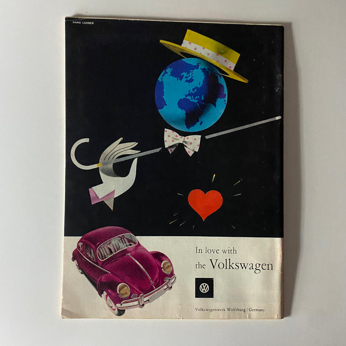 In love with the Volkswagen advertisement from a vintage magazine, showcasing a playful design with a globe and a pink Volkswagen car.