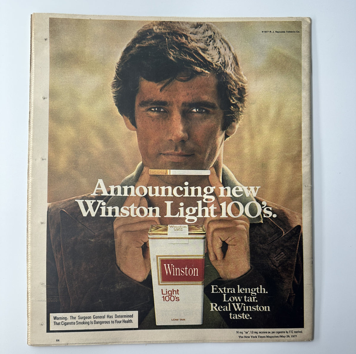 Advertisement for Winston Light 100s cigarettes from The New York Times Magazine, featuring a young man holding a pack of cigarettes with the tagline 'Extra length. Low tar. Real Winston taste.'.
