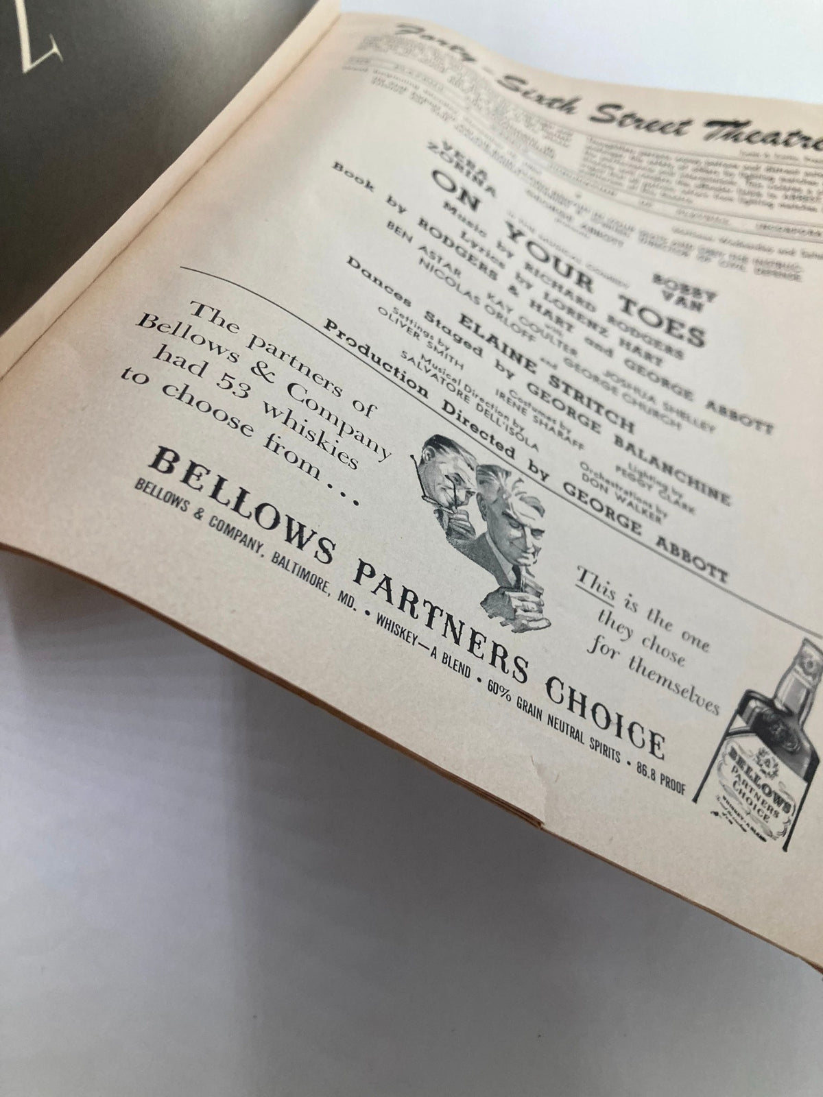 Close-up view of the page in the 1954 Playbill containing information about 'On Your Toes' and a whiskey advertisement from Bellows & Company.