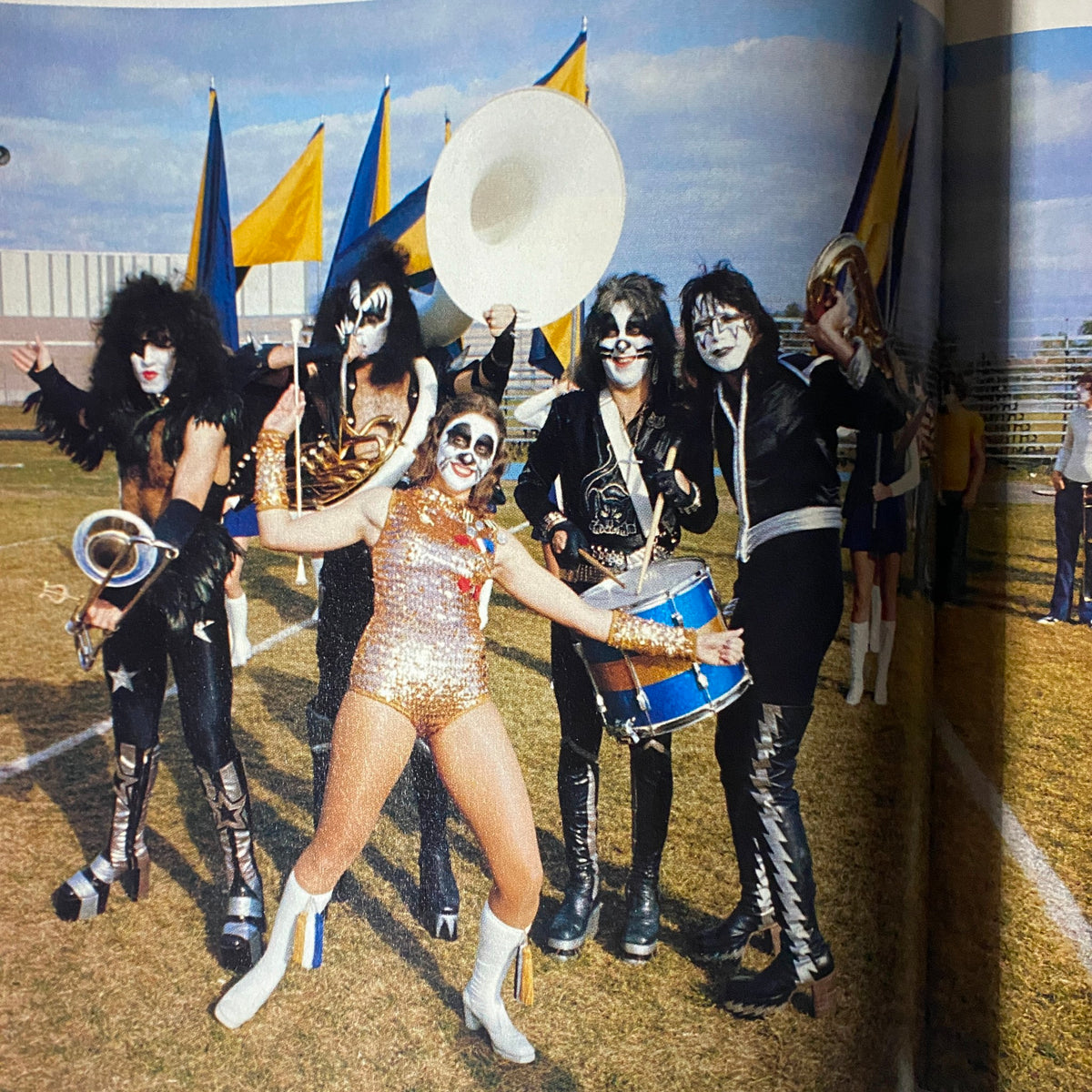 KISS band members and a performer in costume posing on a football field, featured in the 1998 Premiere Issue of Todd McFarlane Presents Kiss Psycho Circus.