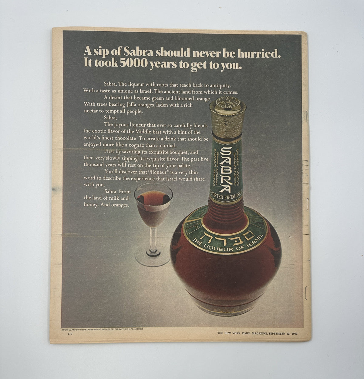 Advertisement in The New York Times Magazine from September 23, 1973, promoting Sabra liqueur with an elegant bottle and glass, along with a description of its rich history and taste experience.
