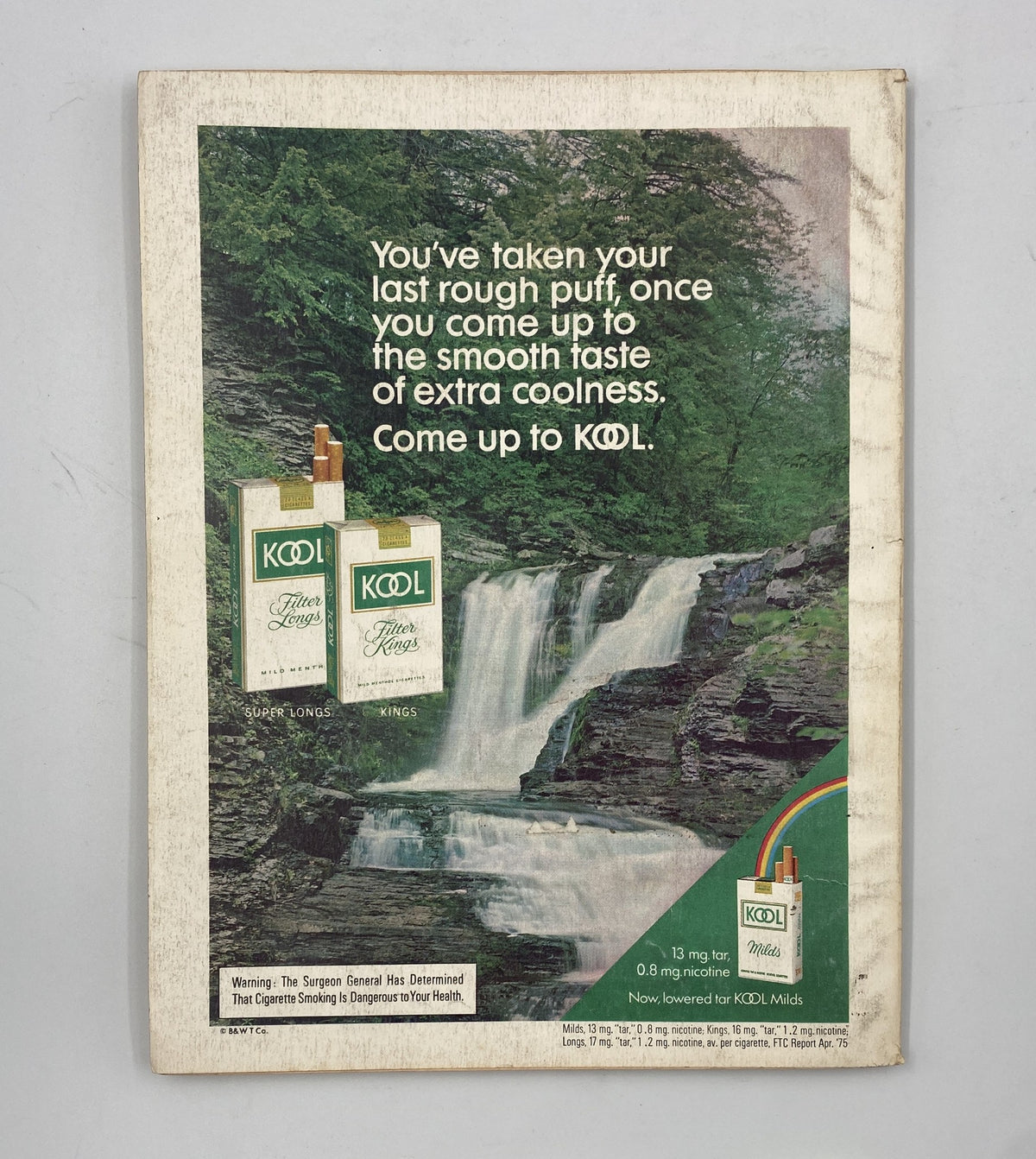 Vintage advertisement from Esquire Magazine March 1976 featuring KOOL cigarettes. The ad showcases a picturesque waterfall scene with the slogan, 'You've taken your last rough puff, once you come up to the smooth taste of extra coolness. Come up to KOOL.' This ad represents the advertising style of the 1970s and highlights the brand's appeal.