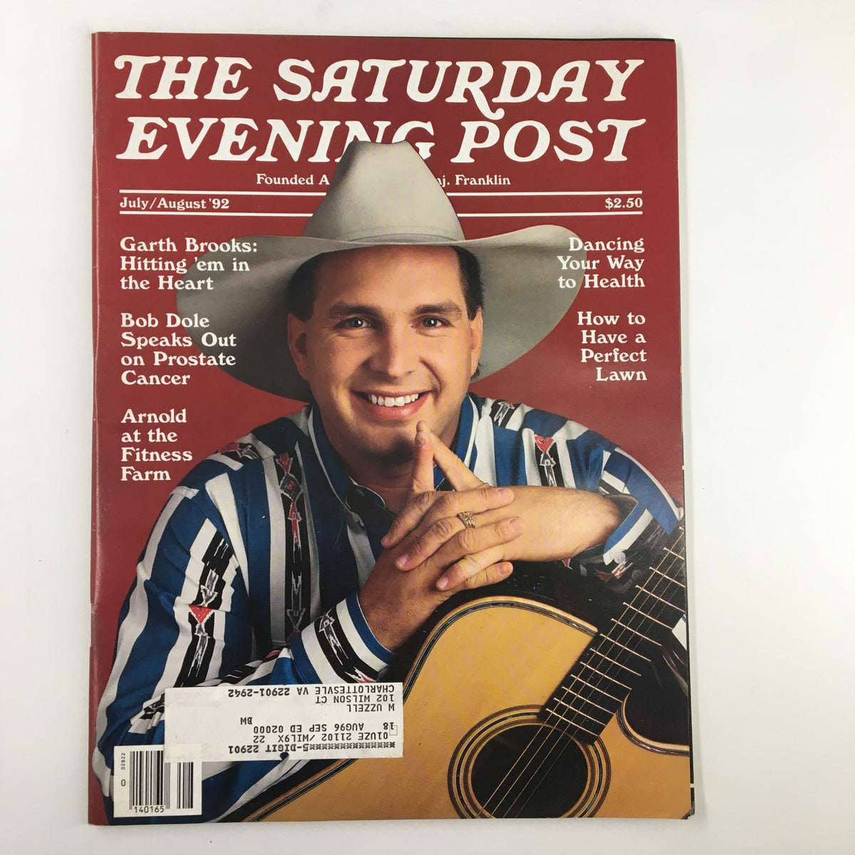 The Saturday Evening Post July 1992 featuring Garth Brooks on the cover, highlighted by the title 'Hitting em' In The Heart', showcasing a portrait of Garth Brooks in a cowboy hat and colorful striped shirt, with his guitar, promoting the magazine's focus on entertainment and Americana.