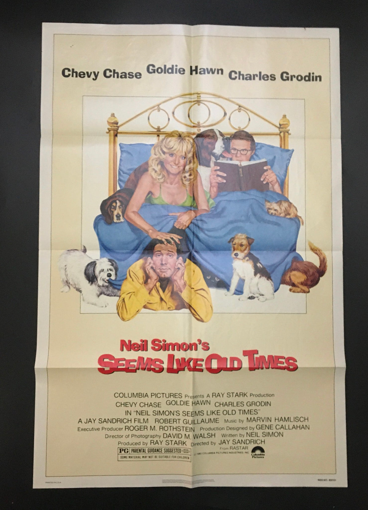 1980 Seems Like Old Times 41" x 27" Original Movie Poster featuring Chevy Chase, Goldie Hawn, and Charles Grodin on a bed surrounded by dogs, showcasing vibrant colors and unique vintage artwork.