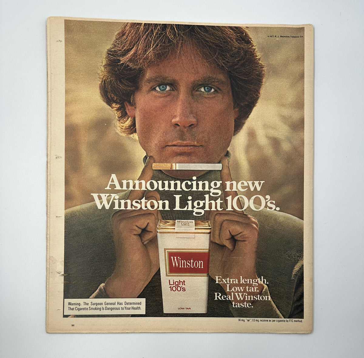 Back cover of The New York Times Magazine April 10, 1977 advertising the new Winston Light 100s cigarettes, featuring a close-up of a man with long hair holding a cigarette pack with an emphasis on the light branding.