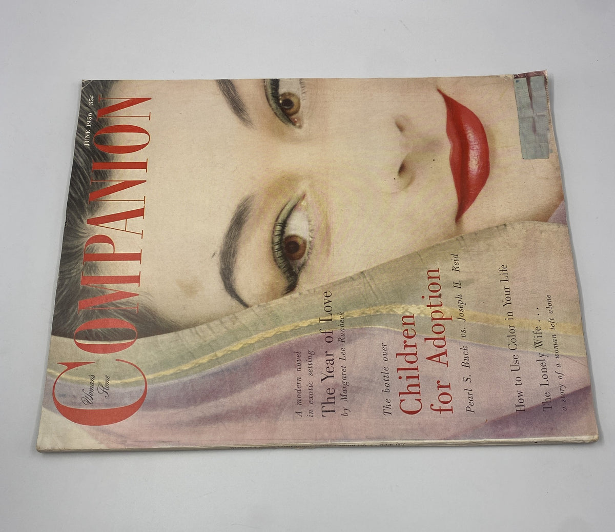 Close-up view of the cover of Woman’s Home Companion Magazine from June 1956 highlighting 'Children for Adoption' and 'The Year of Love' by Margaret Lee Runbeck, with a focus on the model's striking makeup.