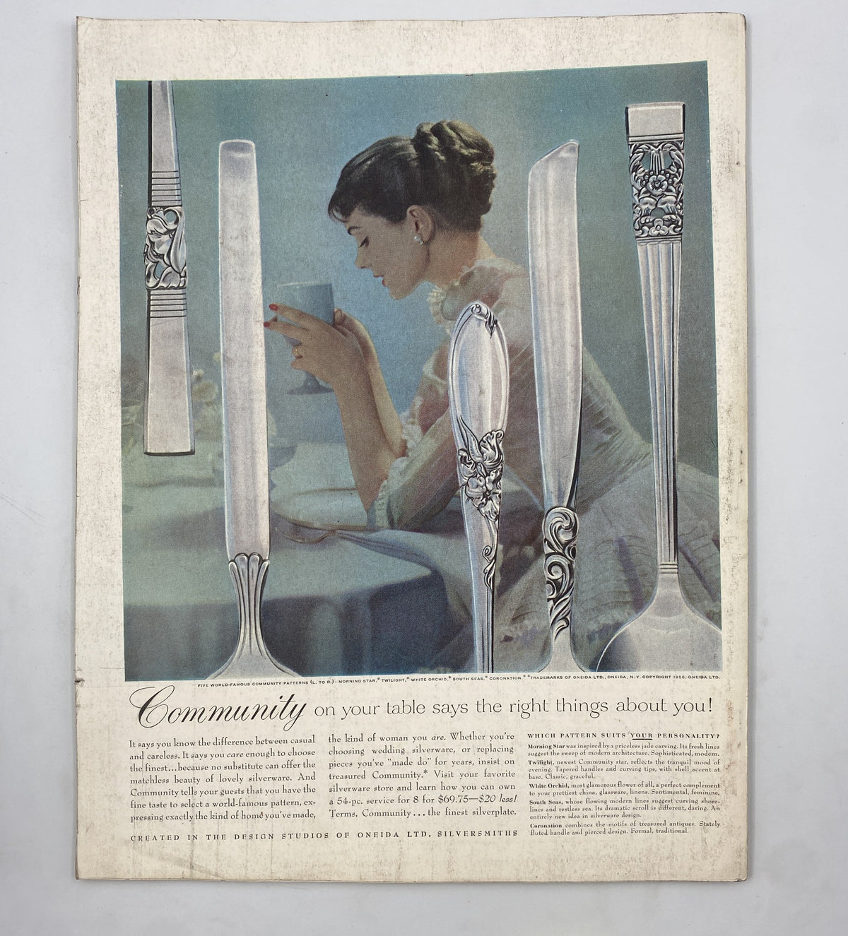 Advertisement page in Woman’s Home Companion Magazine April 1956 showing silverware with the tagline about how community reflects on dining experiences. The ad emphasizes elegance and style in table settings.