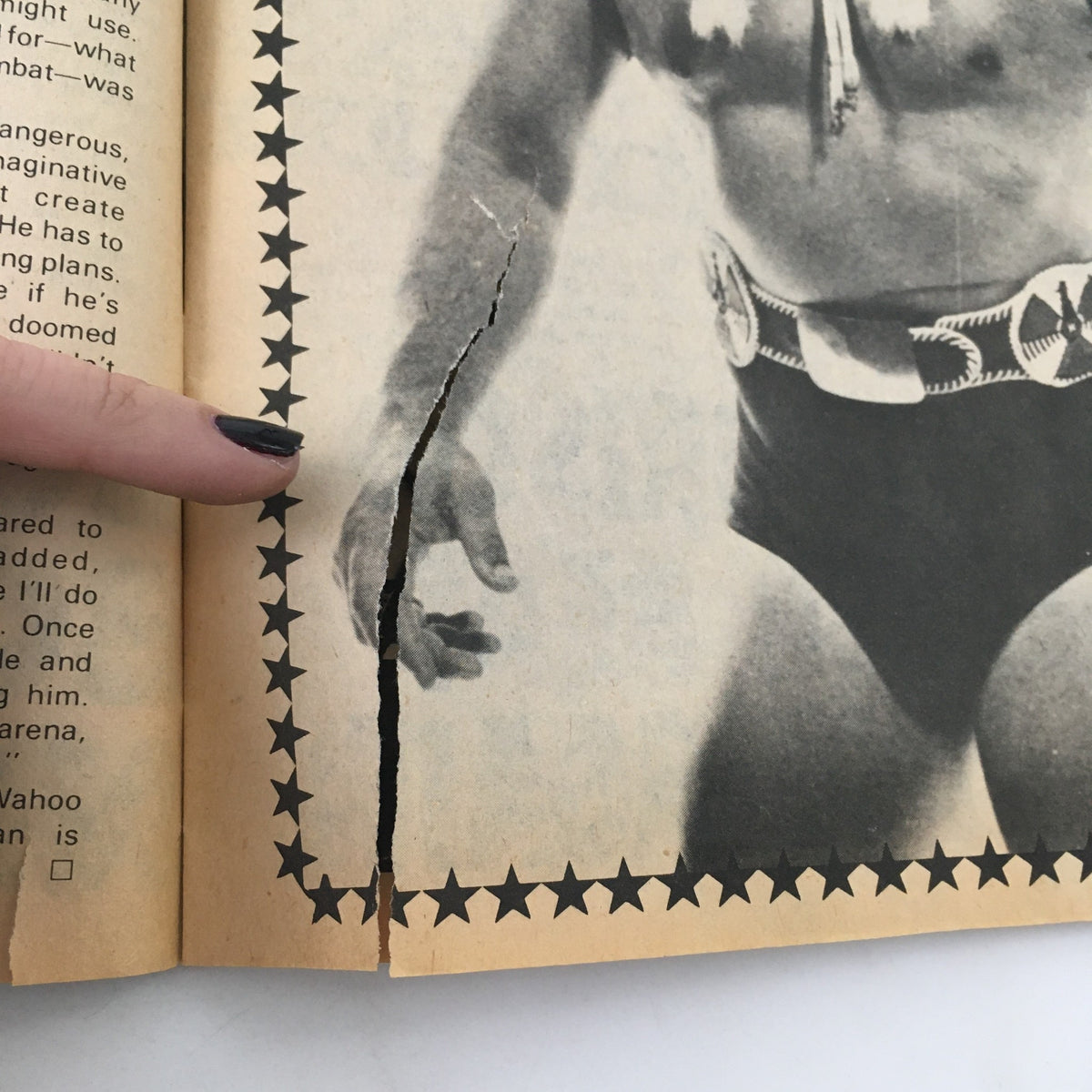 Close-up of a torn page revealing a black and white image of a wrestler, part of the Wrestling Superstars Magazine Spring 1980.