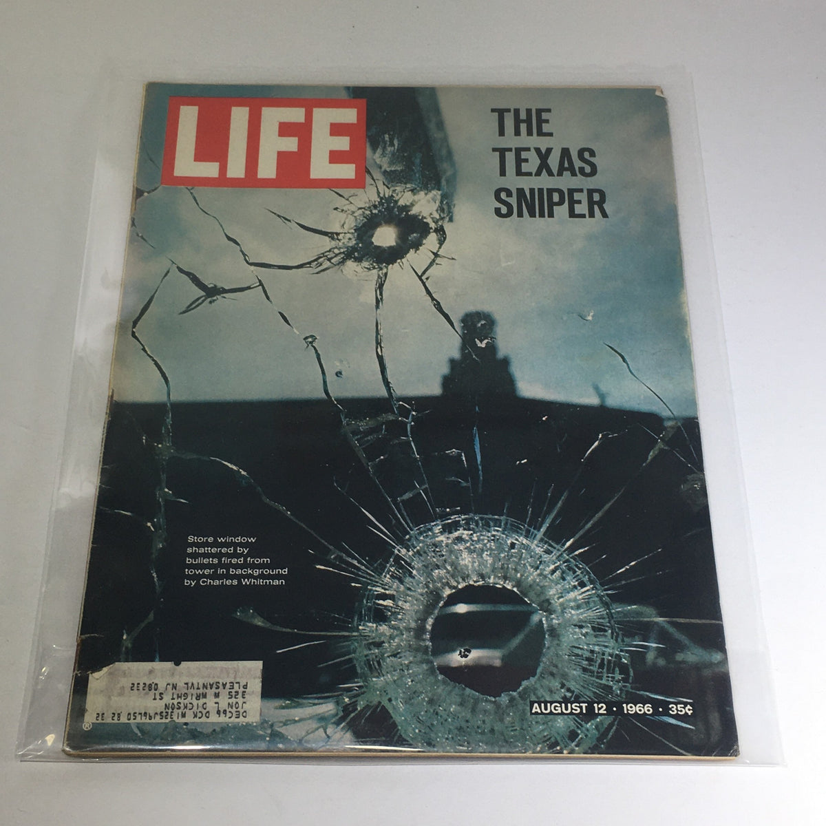 Front cover of VTG Life Magazine from August 12, 1966, featuring a striking image related to the Texas Sniper, Charles Whitman, displaying shattered glass and a bullet hole, highlighting the poignant historical context.