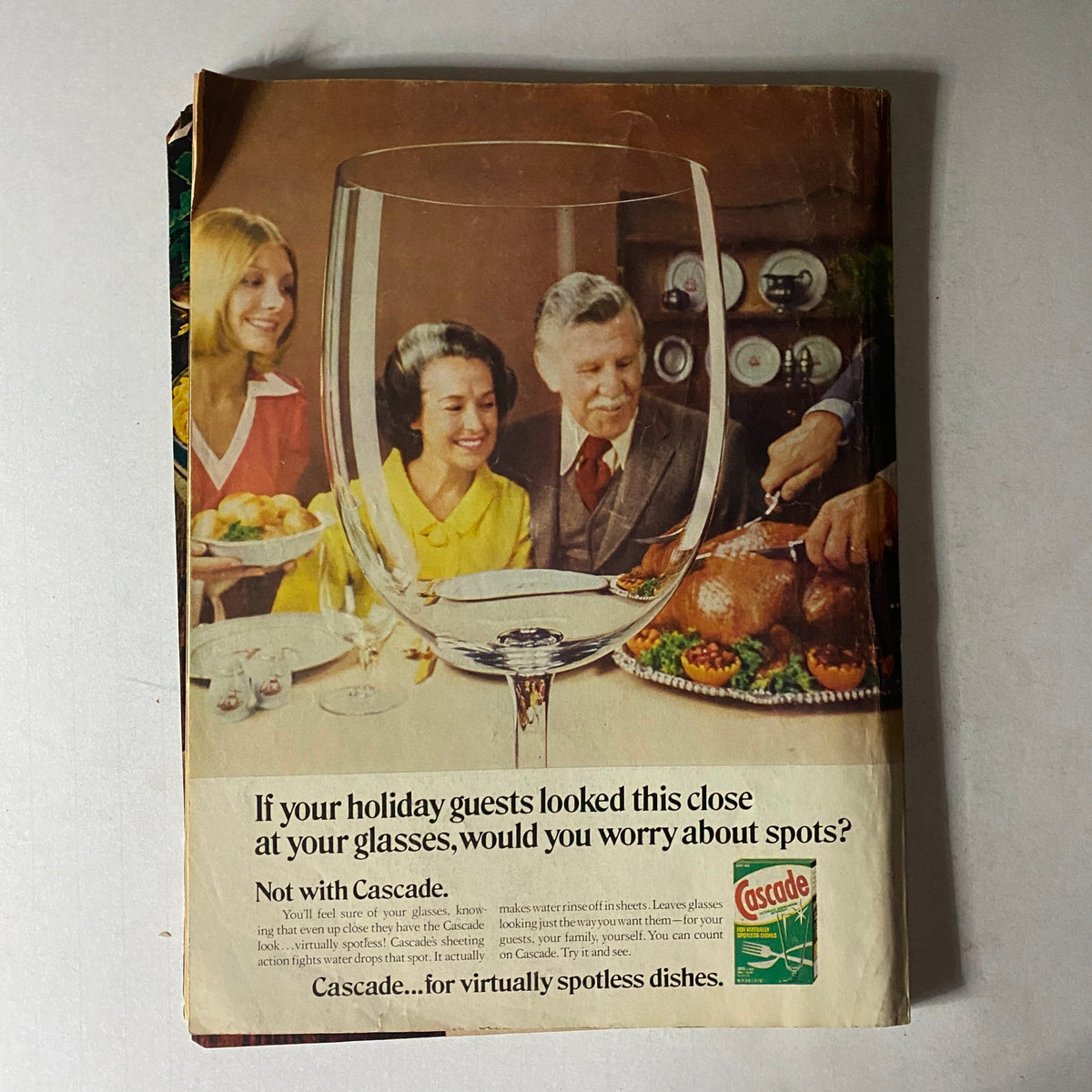 Back cover of Woman's Day Magazine December 1975 advertising Cascade dishwashing detergent, featuring a festive dining scene with family enjoying a holiday meal.