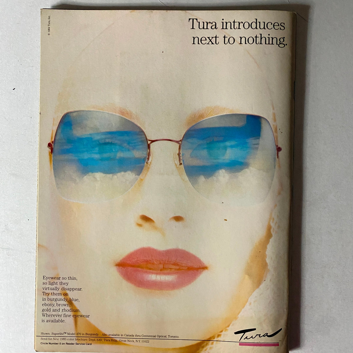 Tura eyewear advertisement from the Savvy Magazine December 1985 showcasing stylish sunglasses, promoting lightweight and fashionable eyewear options for modern women.