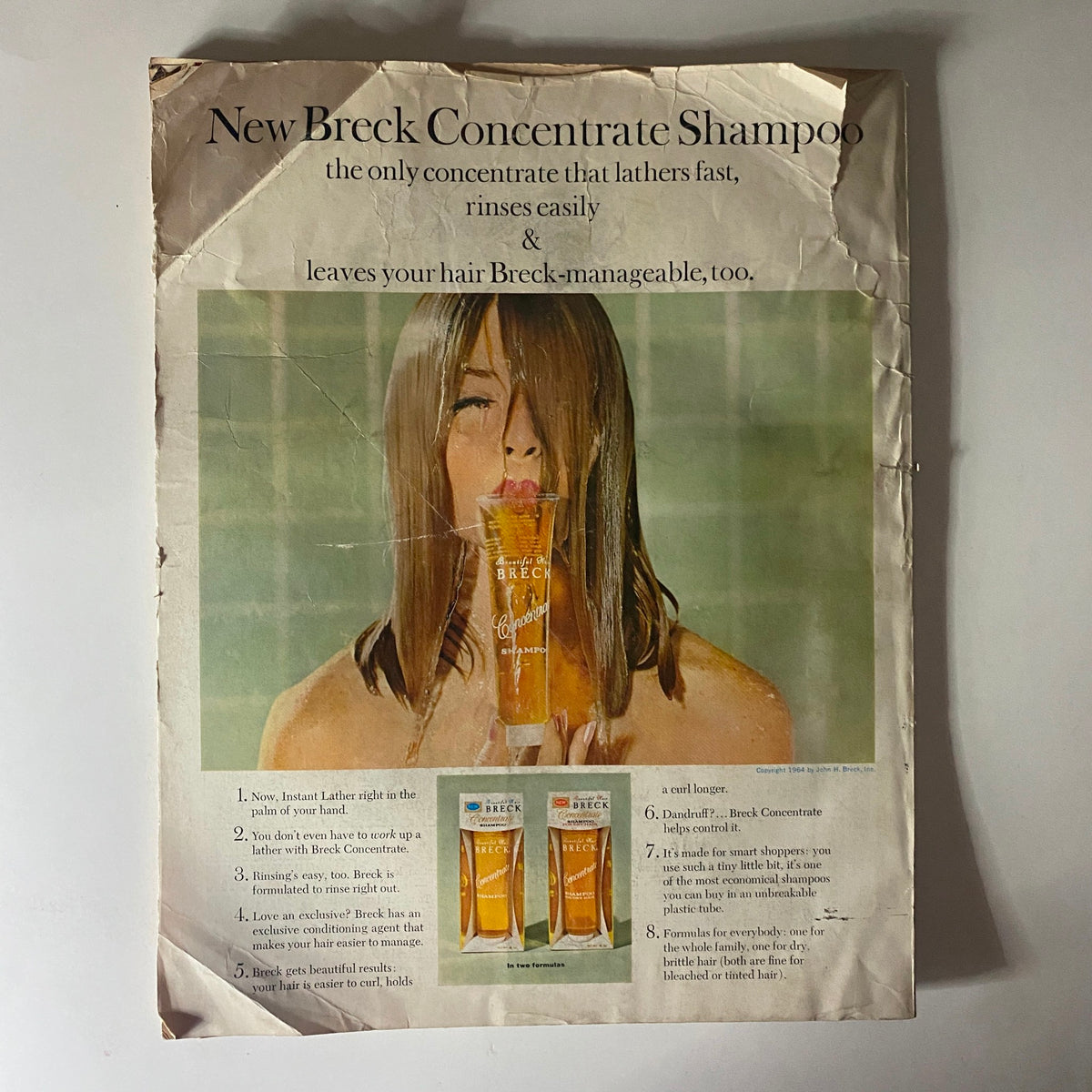 Advertisement for New Breck Concentrate Shampoo featured in vintage magazine from the 1960s, showcasing a model using the product, emphasizing its lathering and rinsing qualities.