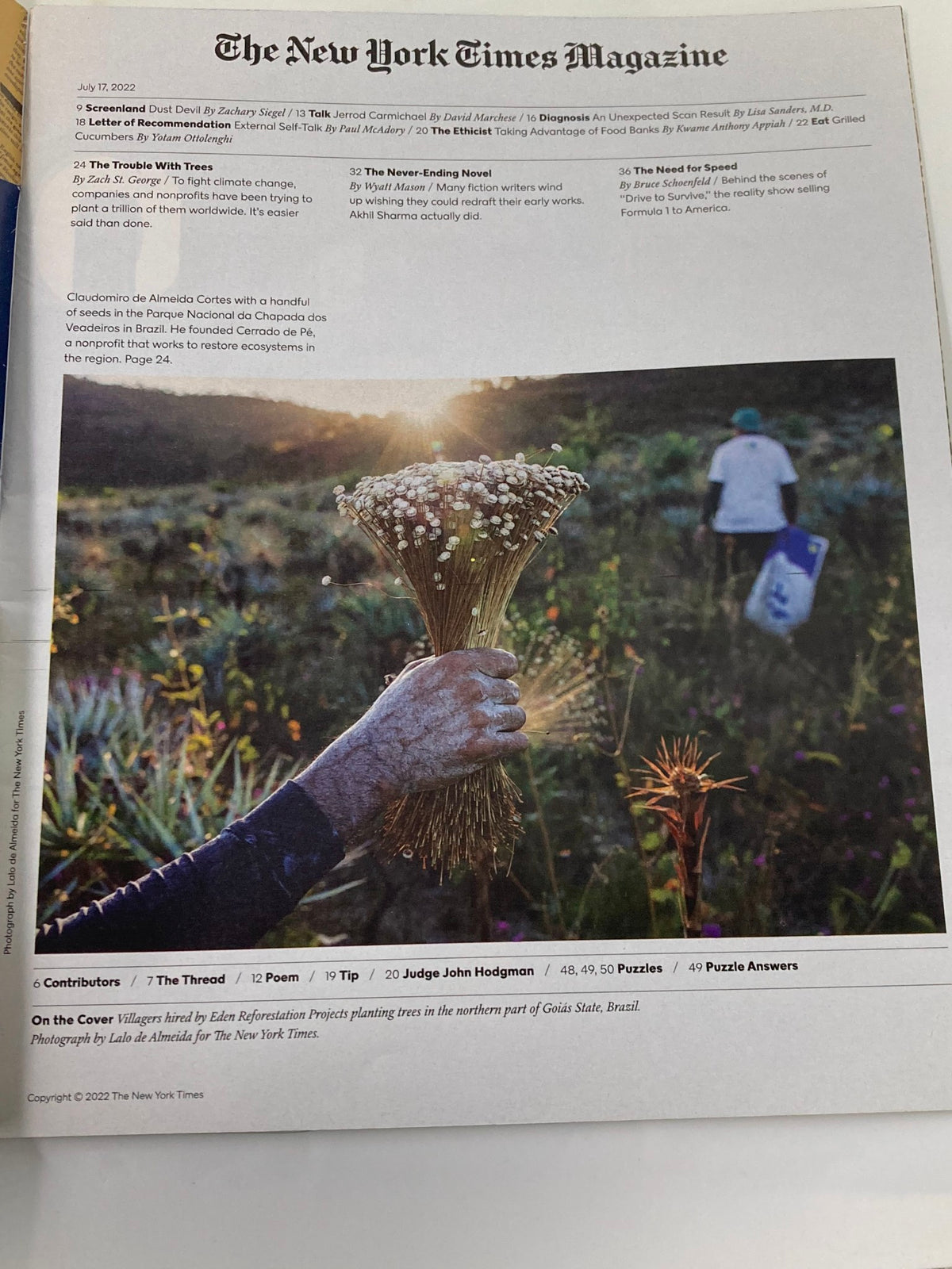 Interior page of The New York Times Magazine July 17 2022 showcasing a close-up of a hand holding flowers, symbolizing the magazine's focus on environmental advocacy and tree planting initiatives.