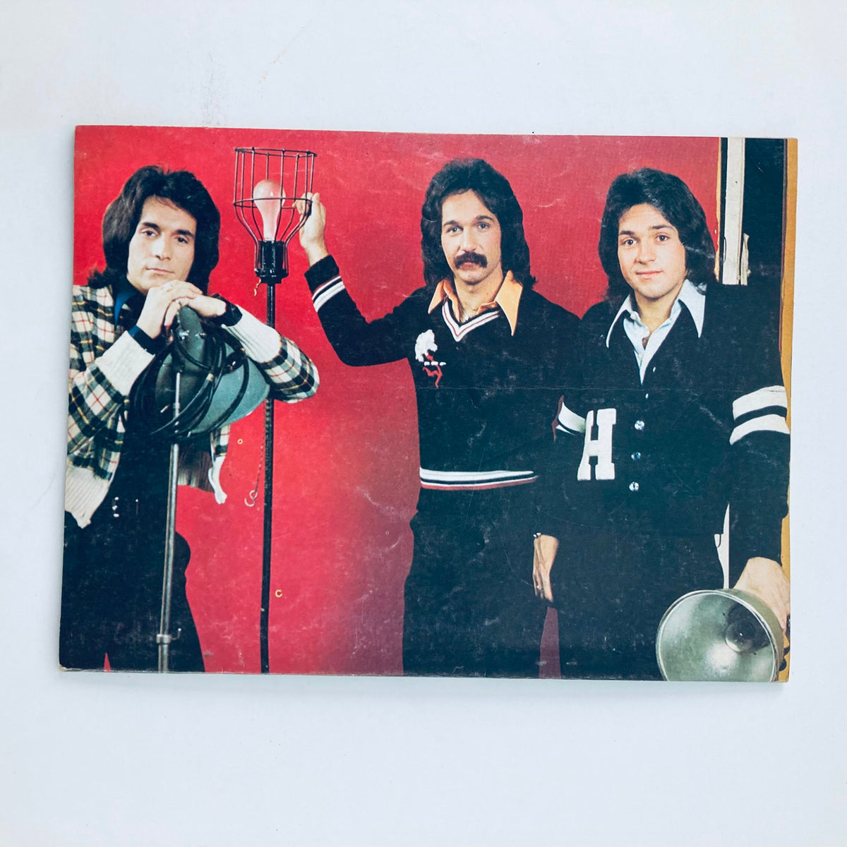 Tiger Beat Magazine October 1975 photo of three male celebrities posing in casual 1970s fashion against a red backdrop.