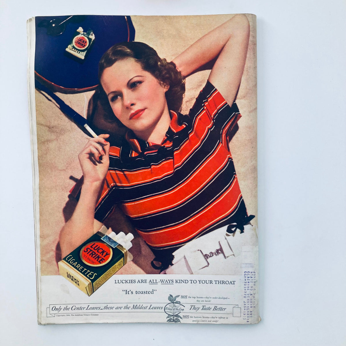 Vintage advertisement from a magazine featuring a woman in a striped shirt holding a cigarette, promoting Lucky Strike Cigarettes, illustrating 1930s fashion and advertising style.