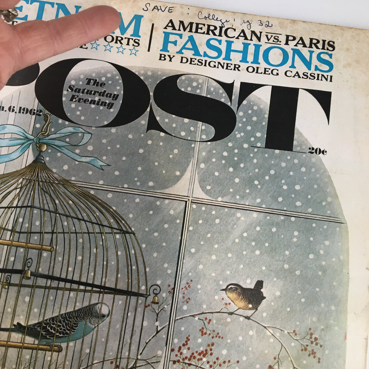 Detailed view of the cover from The Saturday Evening Post January 6, 1962, highlighting the illustration of a birdcage and text about American vs Paris fashions by Oleg Cassini.
