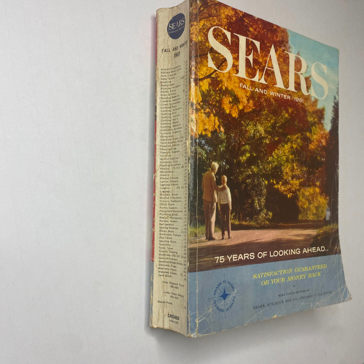 Cover page of the 1961 Sears Fall and Winter Catalog, featuring vibrant autumn colors and a couple walking along a scenic path. The catalog highlights 75 years of Sears and showcases mid-century fashion.