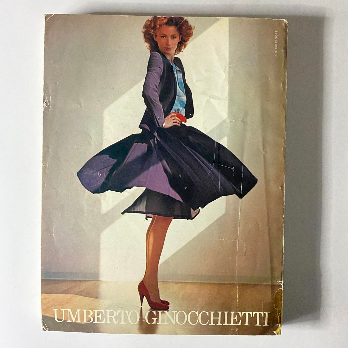 Cover image of an Umberto Ginocchietti catalog featuring a model in a vibrant fashion outfit, capturing the essence of 1980s haute couture.