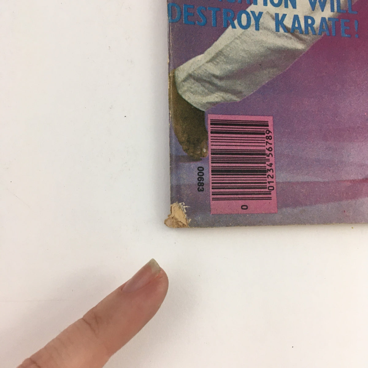 Close-up of the corner of the Official Karate Magazine December 1975 Volume 7 Issue 54 showing minor wear and a finger pointing at the damaged area.
