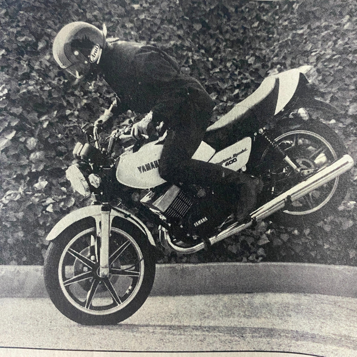 Black and white action shot of a rider performing a stunt on a Yamaha RD400 motorcycle, featured in Motorcyclist Magazine April 1979.