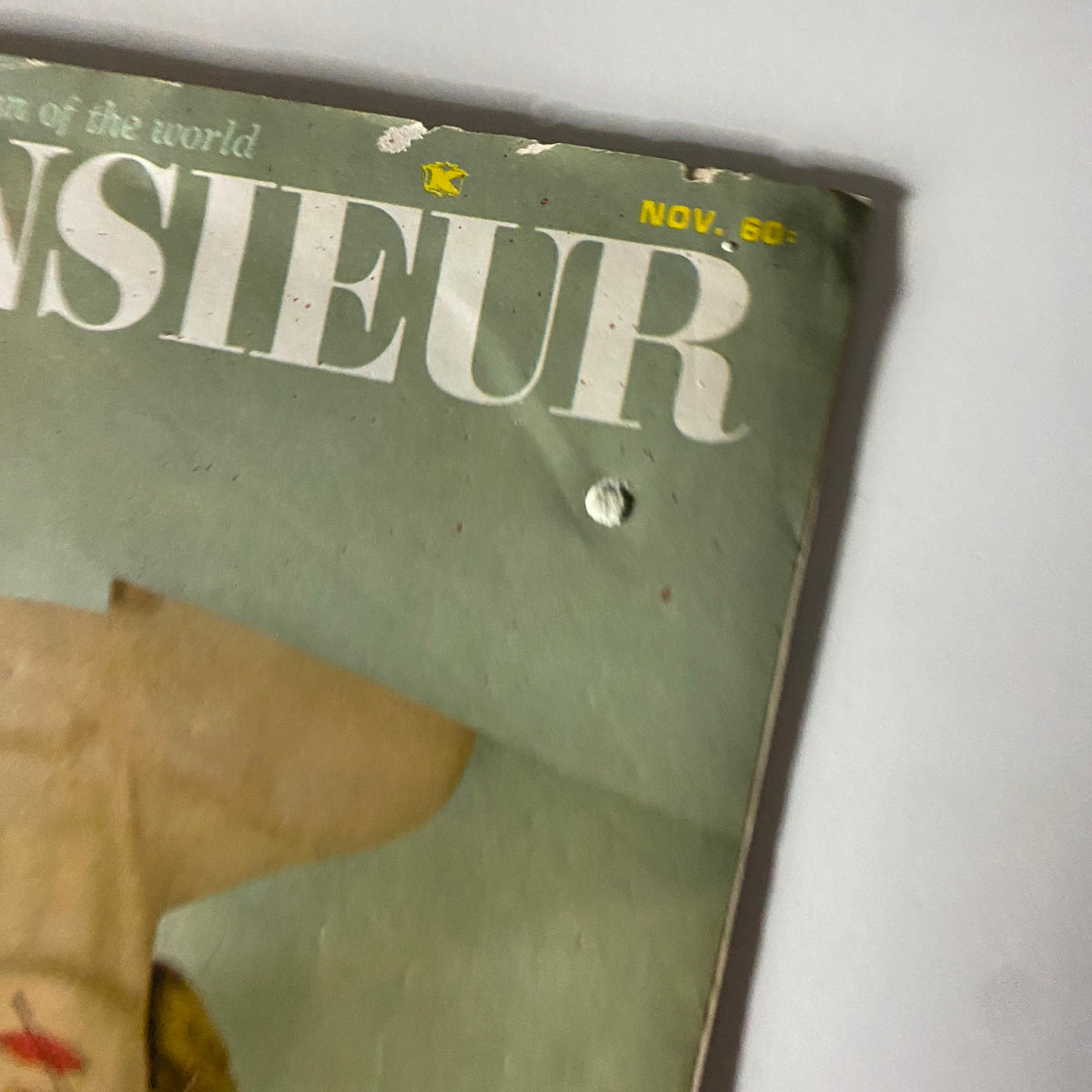 Close-up view of the top corner of Monsieur Magazine November 1965, highlighting the title and date on the distressed cover, emphasizing its vintage appeal.
