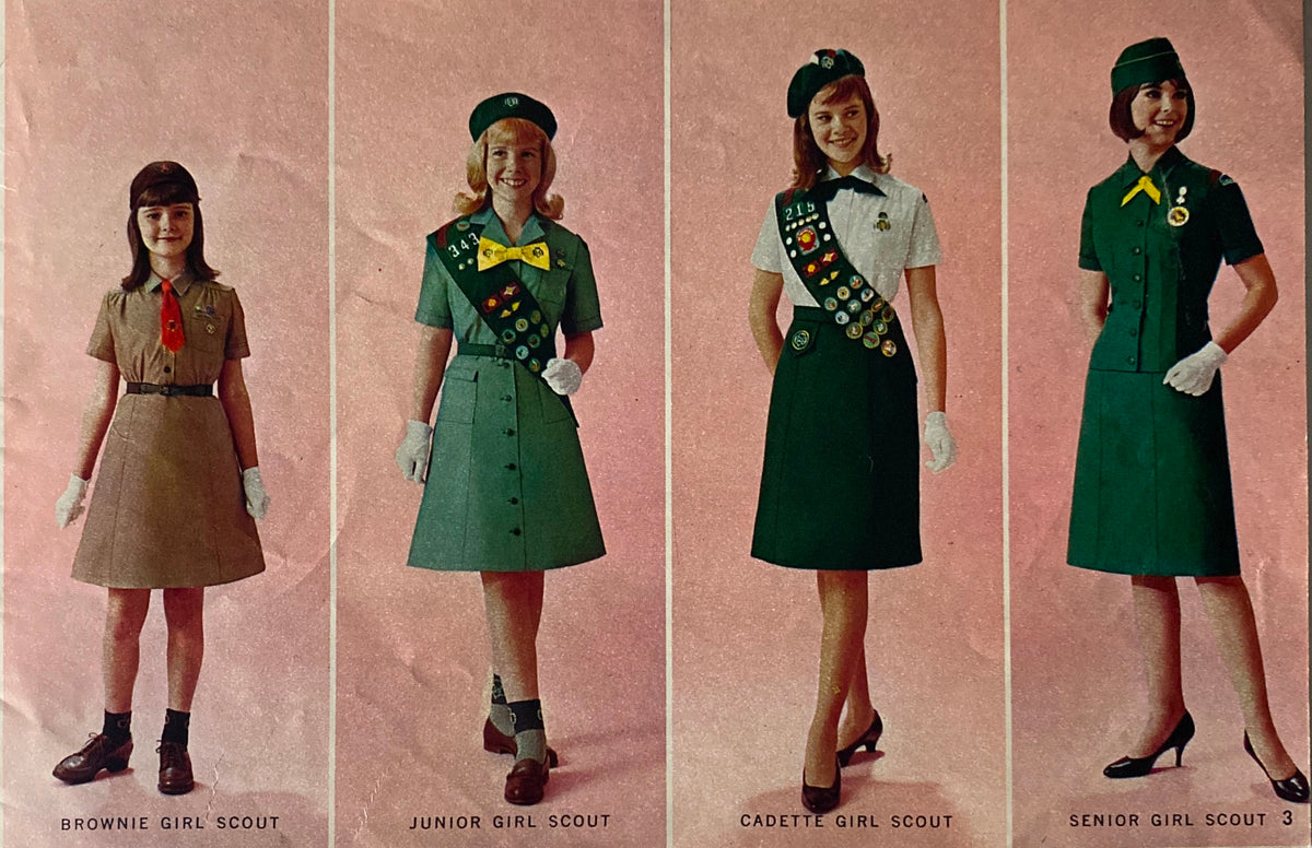 1967 Official Dress Uniforms for Girl Scouts Catalog featuring four Girl Scout uniforms: Brownie, Junior, Cadette, and Senior Girl Scout styles, all displayed on a pink background.