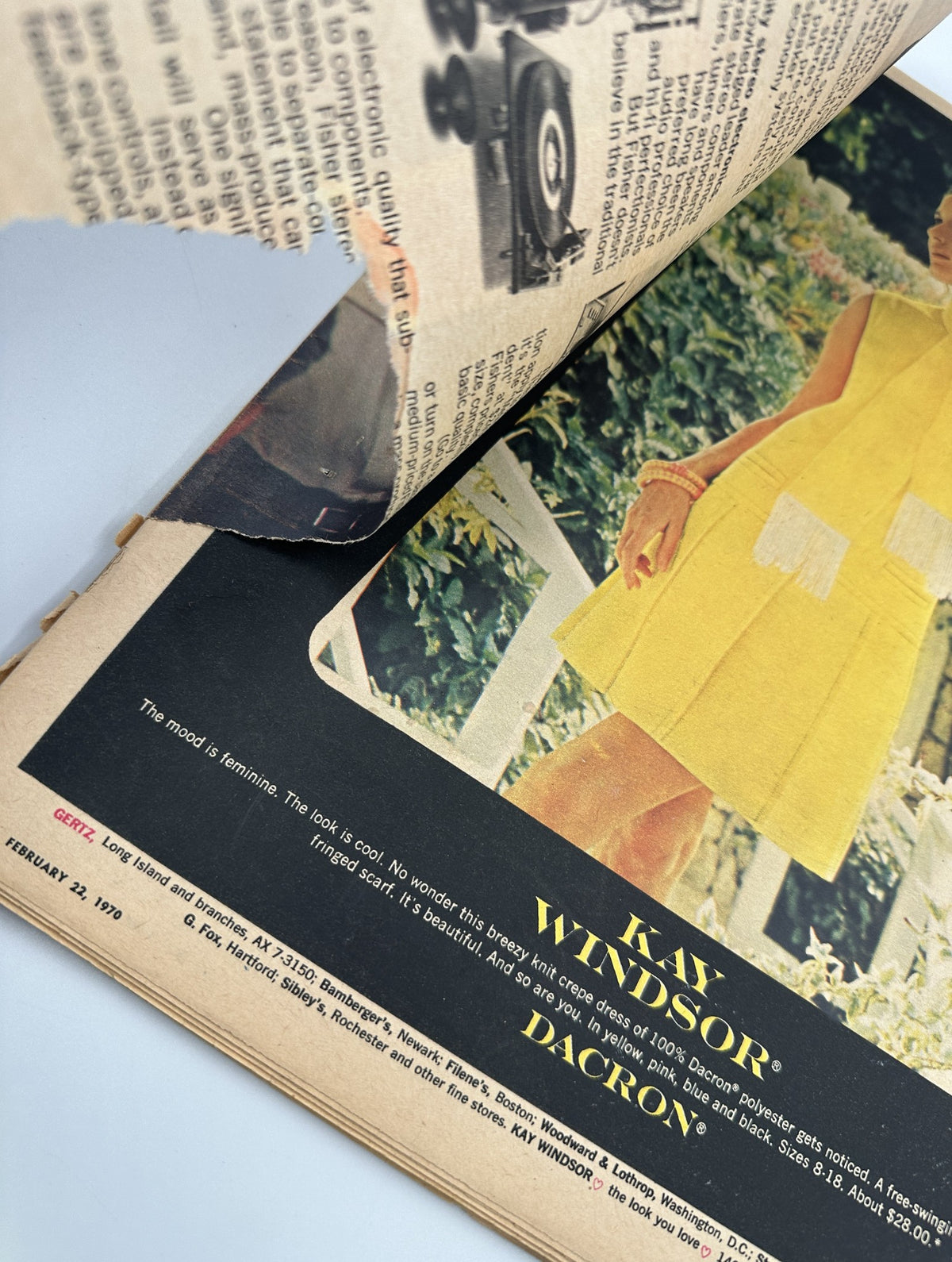 Close-up view of a 1970 advertisement for Kay Windsor on a page from The New York Times Magazine February 22, 1970, depicting a woman in a yellow dress with the caption 'The mood is feminine. The look is cool.'.