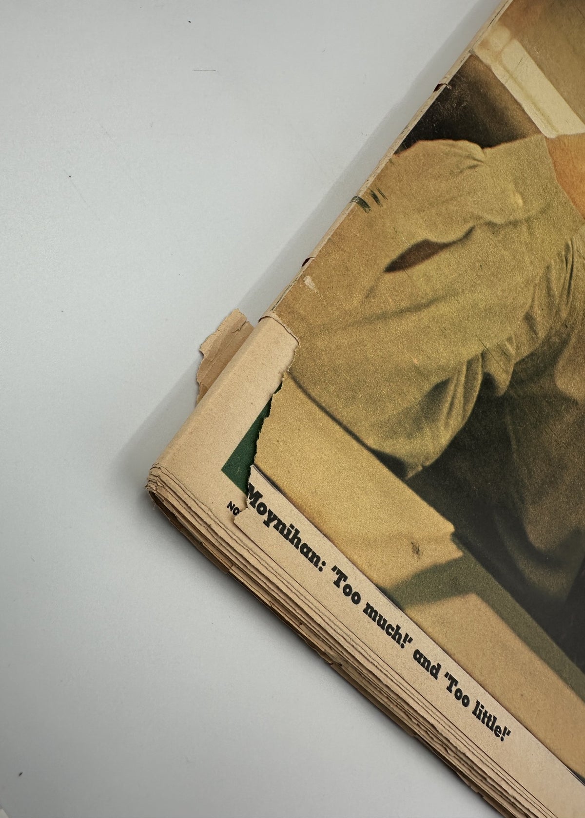Detail shot of the corner of The New York Times Magazine November 2, 1969 cover featuring Pat Moynihan, showing the wear with a torn edge while highlighting the printed title 'Moynihan: Too much!' and 'Too little!'.