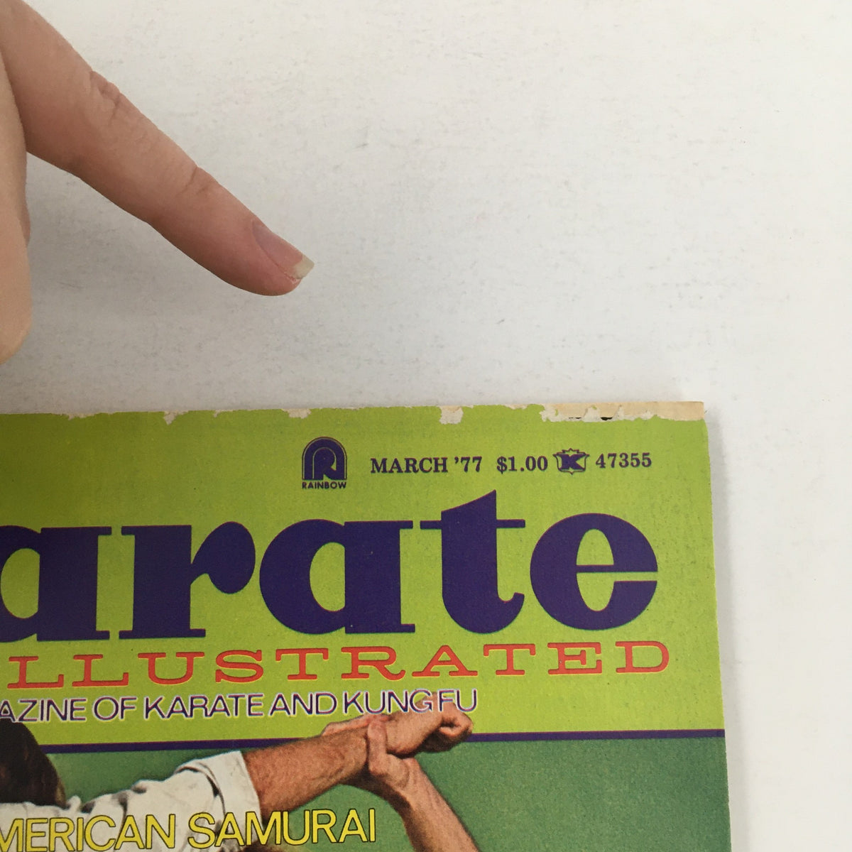 Close-up of Karate Illustrated Magazine March 1977 Vol 8 #3 showing the magazine title with a finger pointing at the cover, highlighting its historical significance in martial arts.