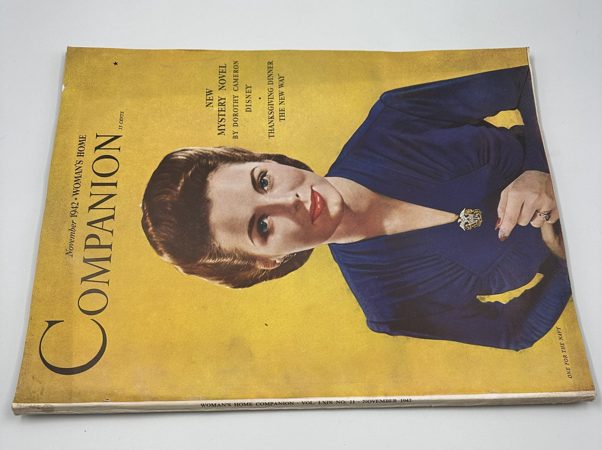 Close-up view of Woman’s Home Companion Magazine November 1942 cover, showcasing a woman in a blue dress, highlighting a new mystery novel by Dorothy Cameron Disney and Thanksgiving dinner themes.