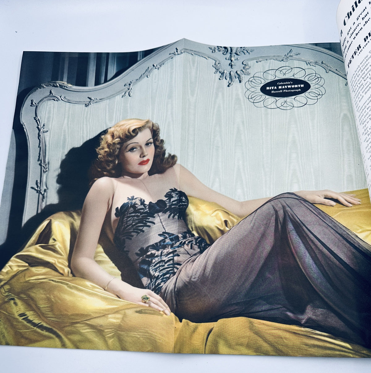 Stunning color portrait of a woman reclining glamorously on a bed, showcasing a stylish dress and 1940s beauty. From Esquire Magazine, November 1942, featuring Varga artwork of Rita Hayworth.