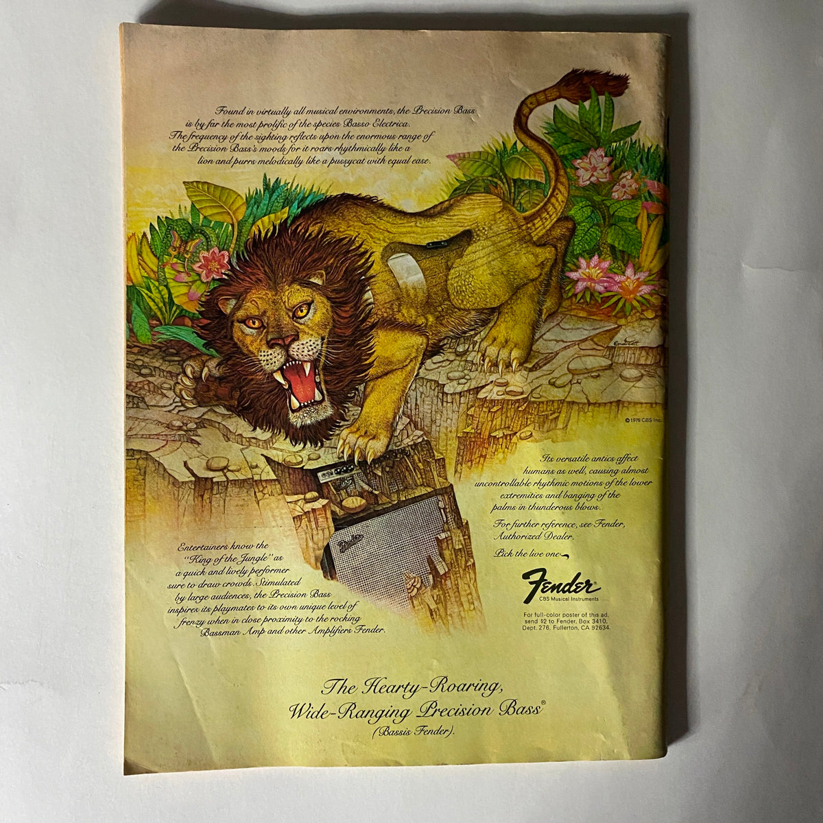 Vintage advertisement for Fender Precision Bass featuring a roaring lion and colorful floral design, dated 1976. Associated with the VTG Crawdaddy Magazine November 1976 titled 'Big Mac Under the Golden Arches'.