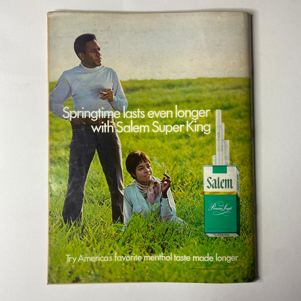 Advertisement in Ebony Magazine April 1970 for Salem Super King cigarettes, showcasing a couple in a grassy field, emphasizing a vibrant lifestyle.