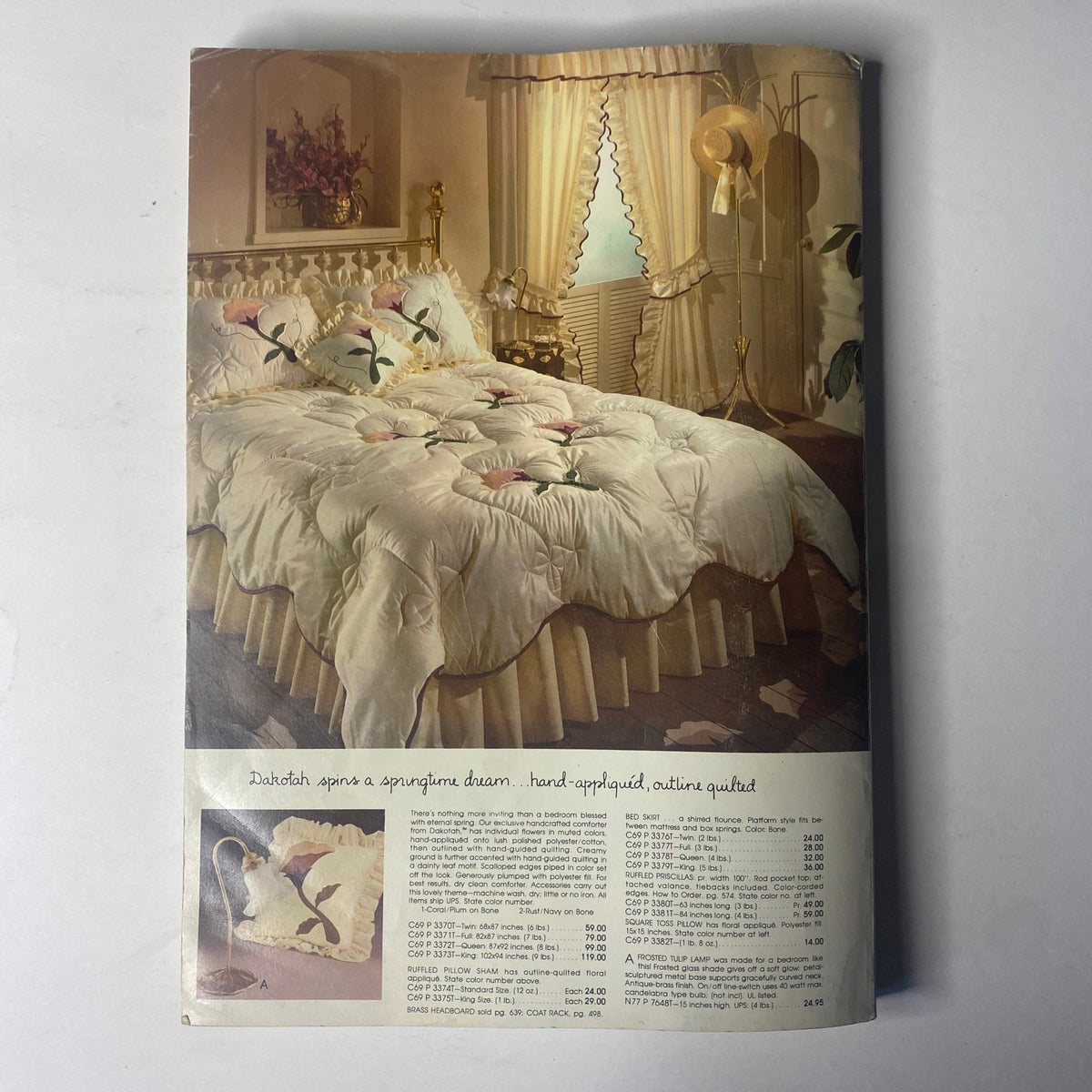 Cover page of the 1980 Spiegel Fall and Winter Catalog featuring elegant home decor with a springtime theme. The image illustrates a beautifully styled bed with floral patterns and decorative accents, showcasing high-quality quilting and design reminiscent of luxurious 1980s fashion.