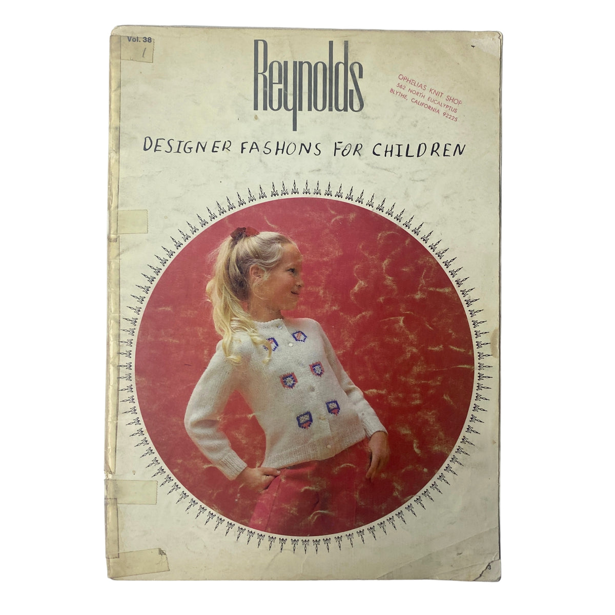 Cover of the 1980s Reynolds Designer Fashions for Children Catalog featuring a girl in a white Fair Isle sweater with colorful patches on the front, set against a vibrant pink background.