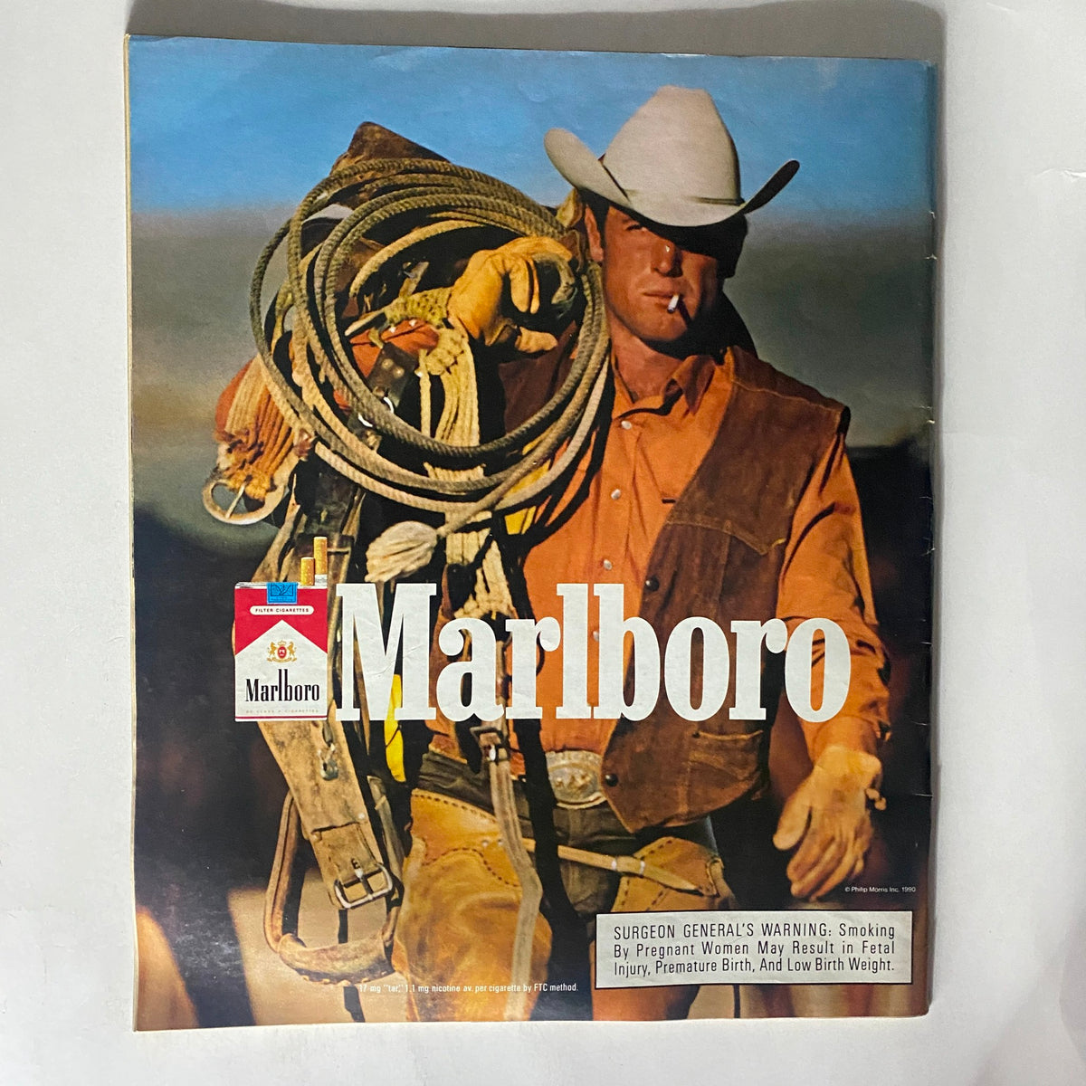 Cover of a vintage Marlboro magazine advertisement featuring a cowboy with ropes, representing classic Americana and western themes.