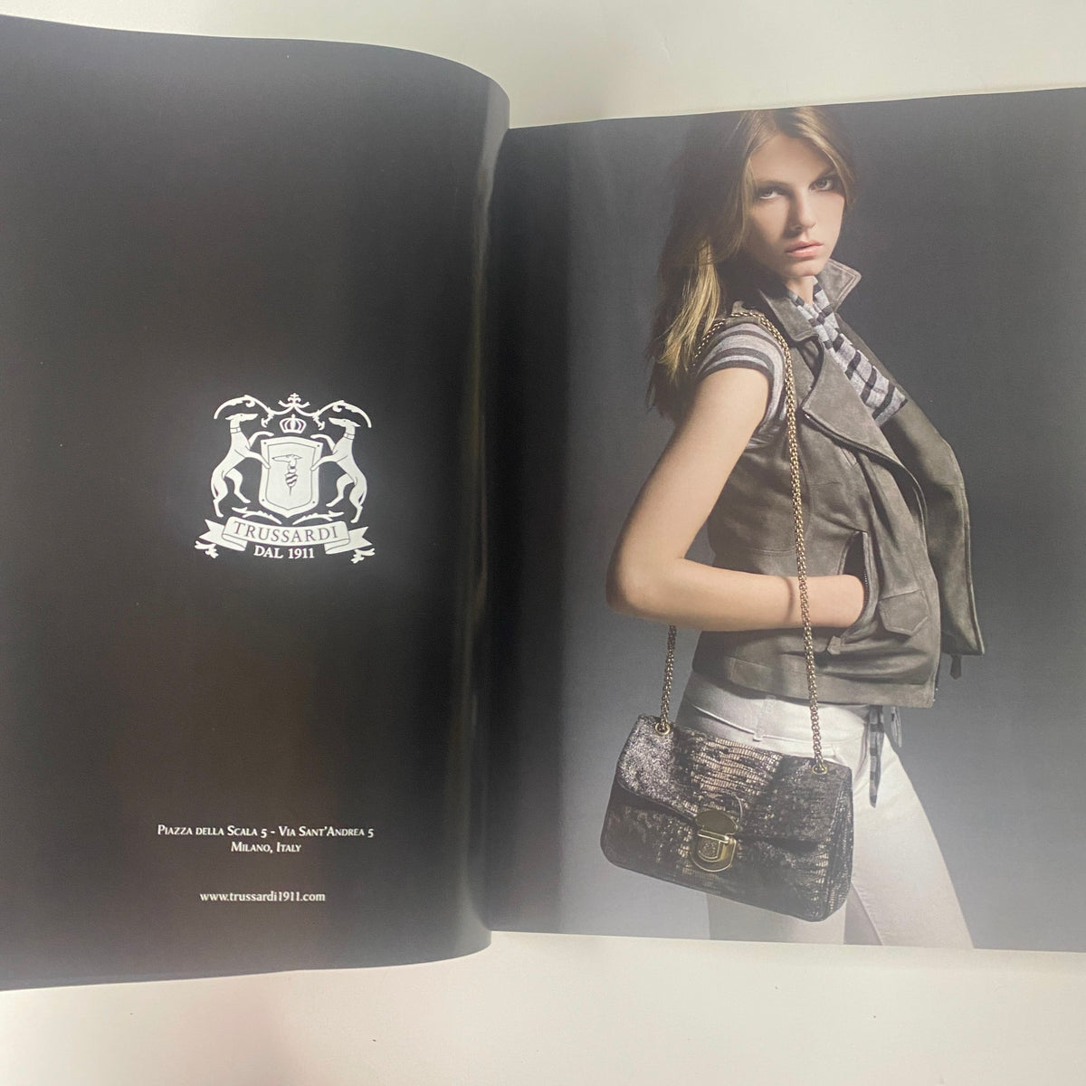 Interior page from the 2009 First Love Spring and Summer Catalog featuring a Trussardi advertisement with a model in stylish attire, emphasizing the brand's elegance.