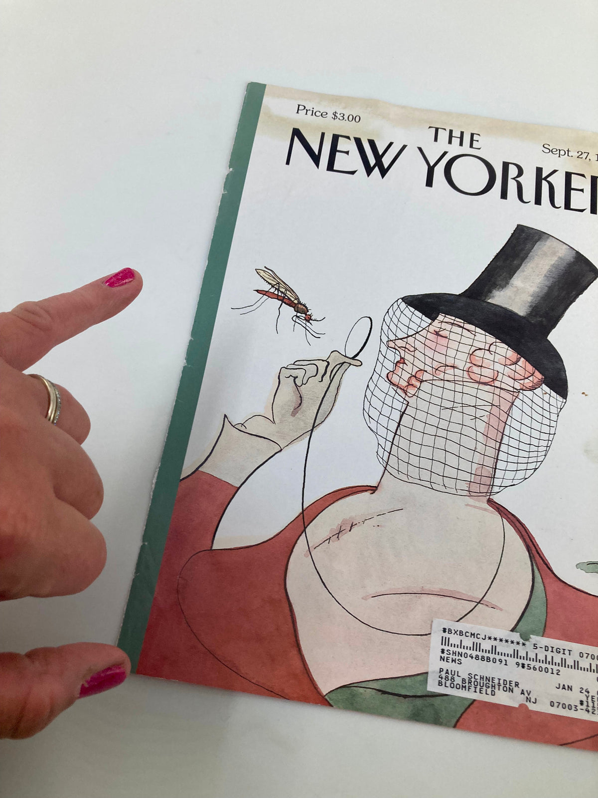 Detail shot of The New Yorker cover dated September 27, 1999, titled 'Buzz City' by Harry Bliss, with a focus on the man's top hat and the mosquito, while a finger points towards the illustration.