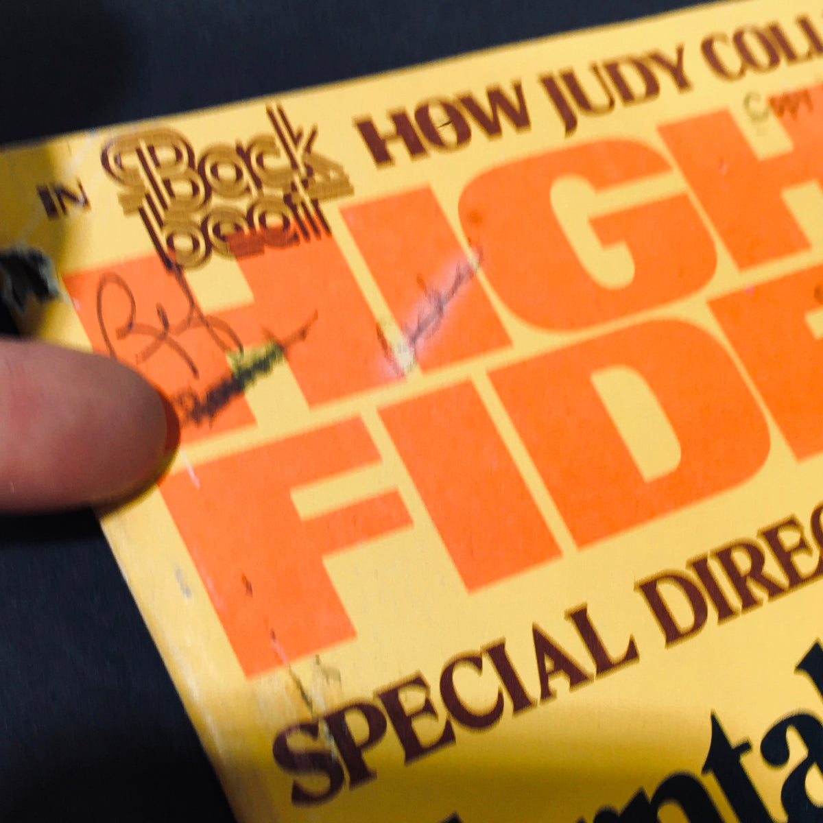 Detailed view of the cover of High Fidelity Magazine from April 1977 with minor wear marks and a finger pointing at the corner damage.