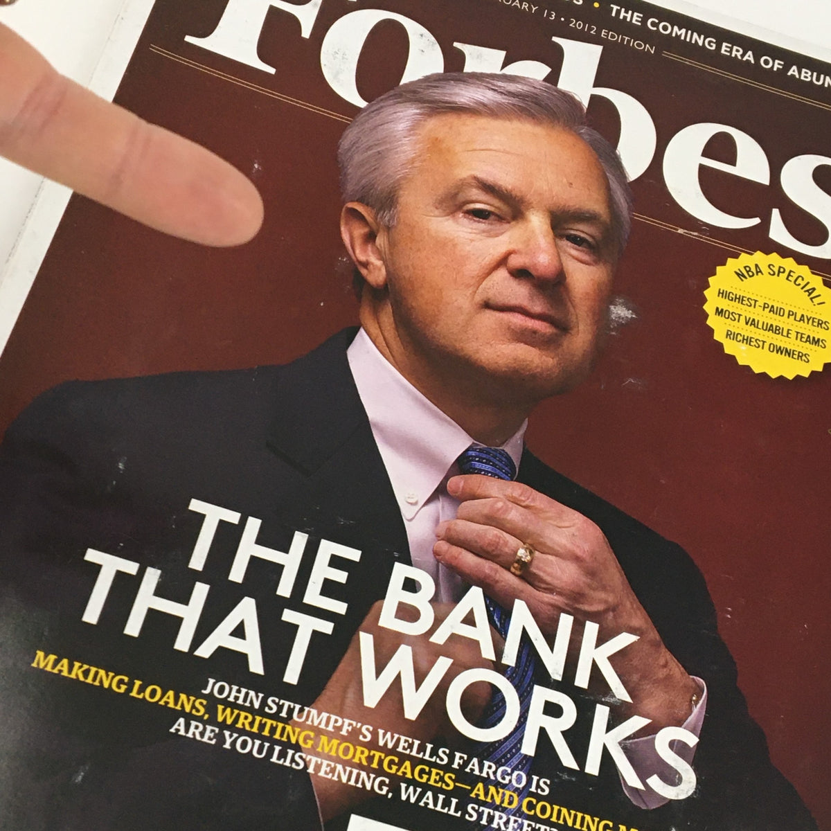 Close-up of Forbes Magazine cover from February 13, 2012, showcasing the headline 'The Bank That Works' with John Stumpf's portrait, emphasizing Wells Fargo's financial solutions.