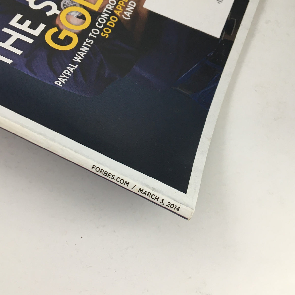 Close-up view of the edge of Forbes Magazine dated March 3, 2014, showcasing the publication date and details related to Paypal's influence in the financial technology sector.