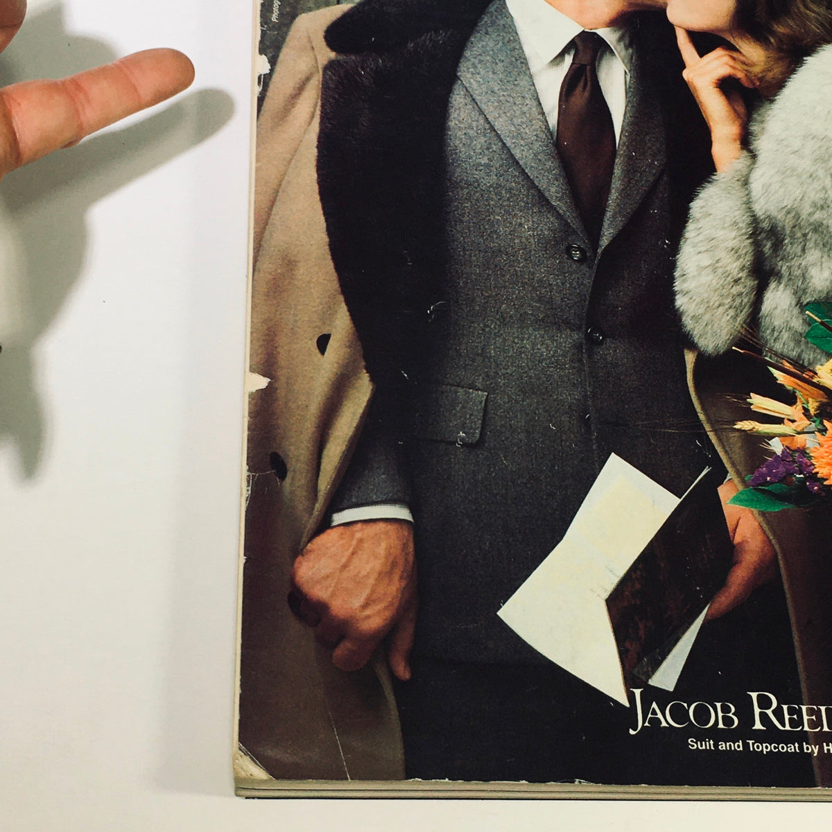 Detailed view of a stylish gentleman in a suit with a furry coat, holding a magazine page from Philadelphia Magazine November 1980 - The New Chinese Restaurants.