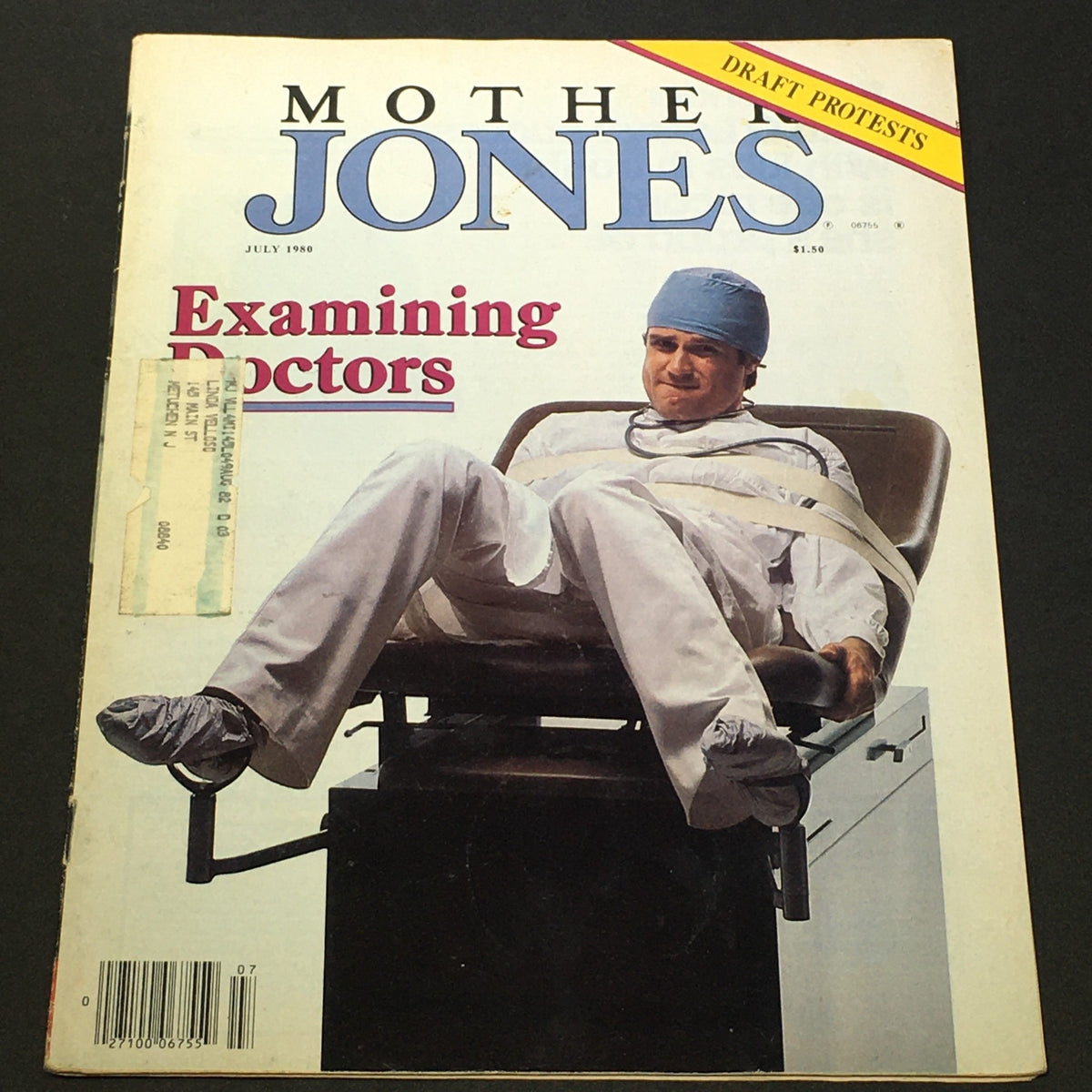 Vintage Mother Jones Magazine July 1980 cover featuring a doctor in scrubs, seated in a chair with restraints, highlighting themes of examining doctors and draft protests.