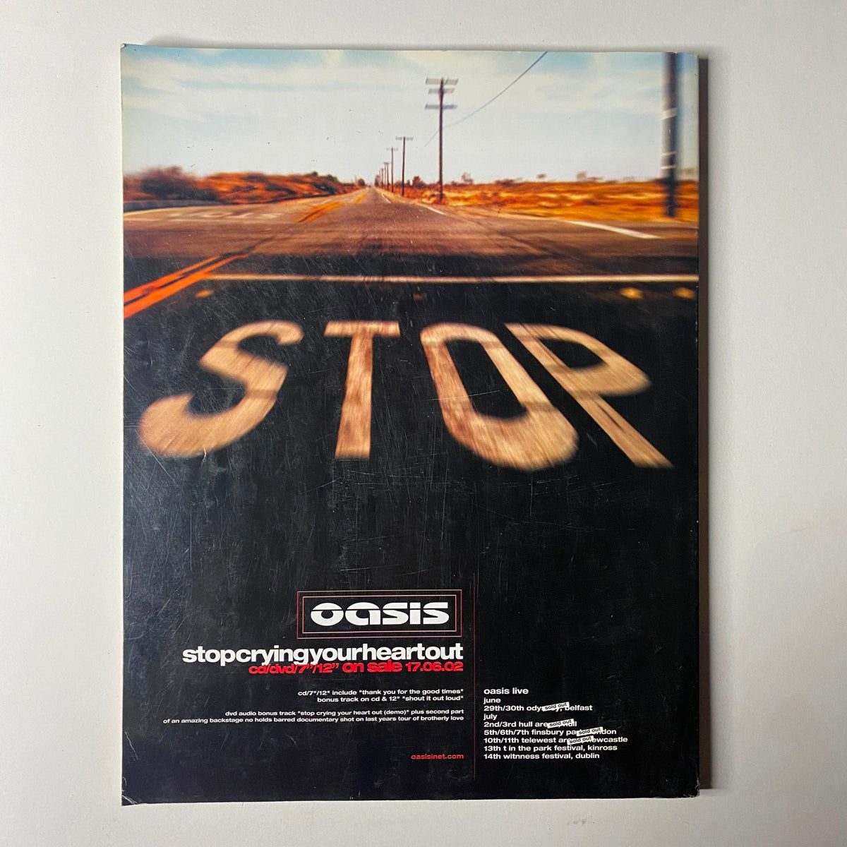 Back cover of Uncut UK Magazine July 2002, featuring a visually striking advertisement for Oasis's single 'Stop Crying Your Heart Out' with a blurred road scene.