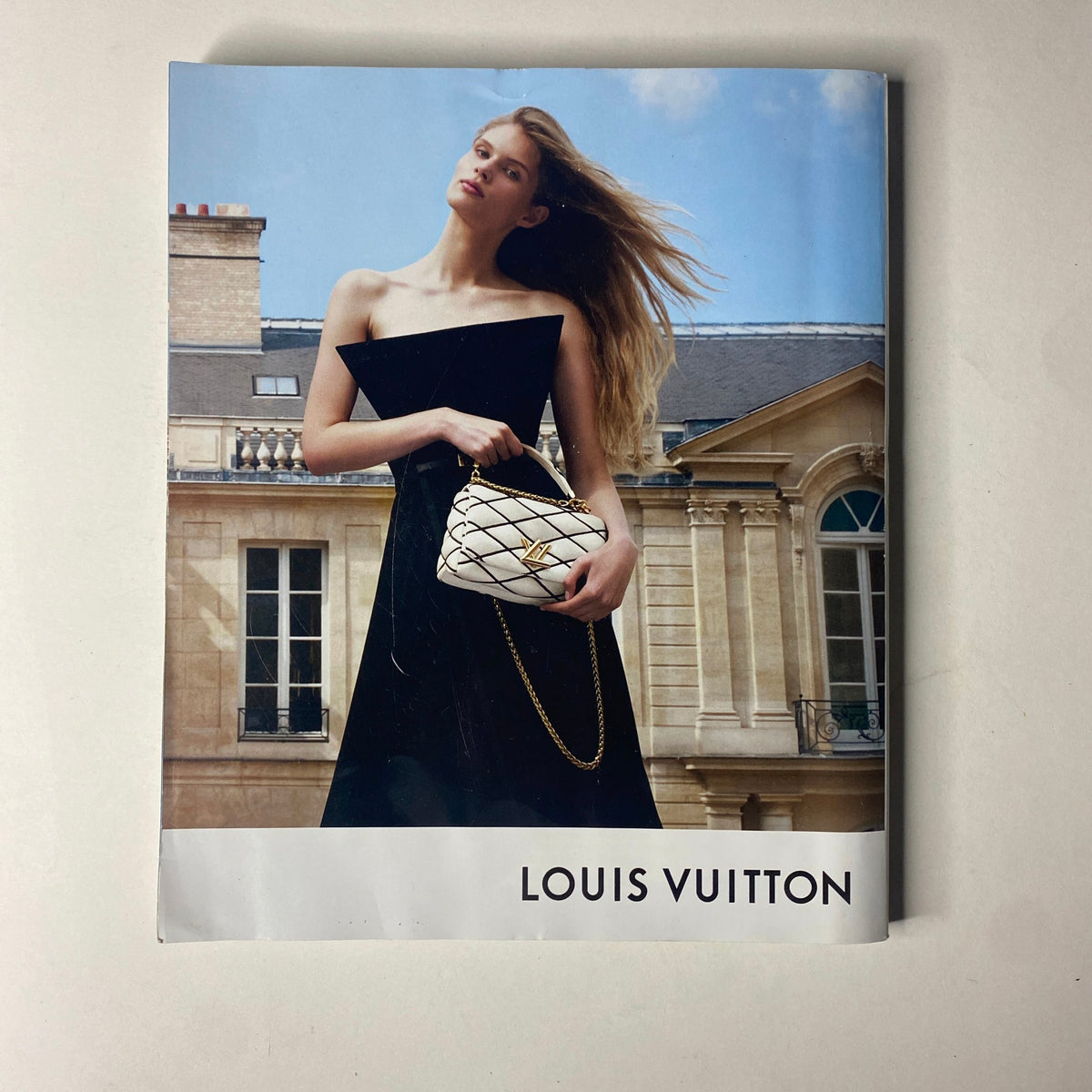 Vogue Magazine September 2023 displaying an elegant Louis Vuitton advertisement, featuring a model in a chic black dress holding a luxury handbag against a chic Parisian architecture.