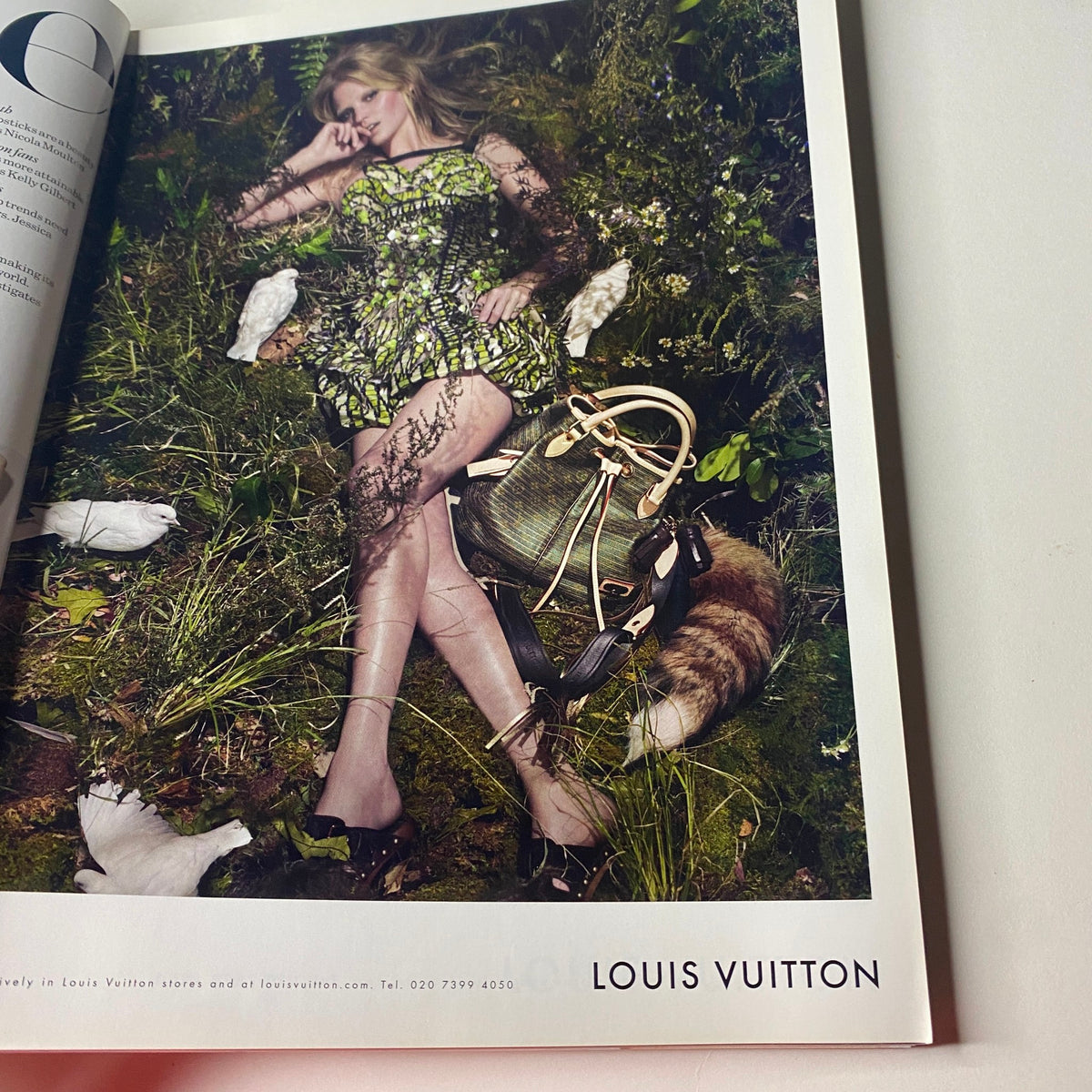 Ad page from Vogue British Magazine April 2010 featuring a Louis Vuitton model surrounded by nature and fashionable accessories.