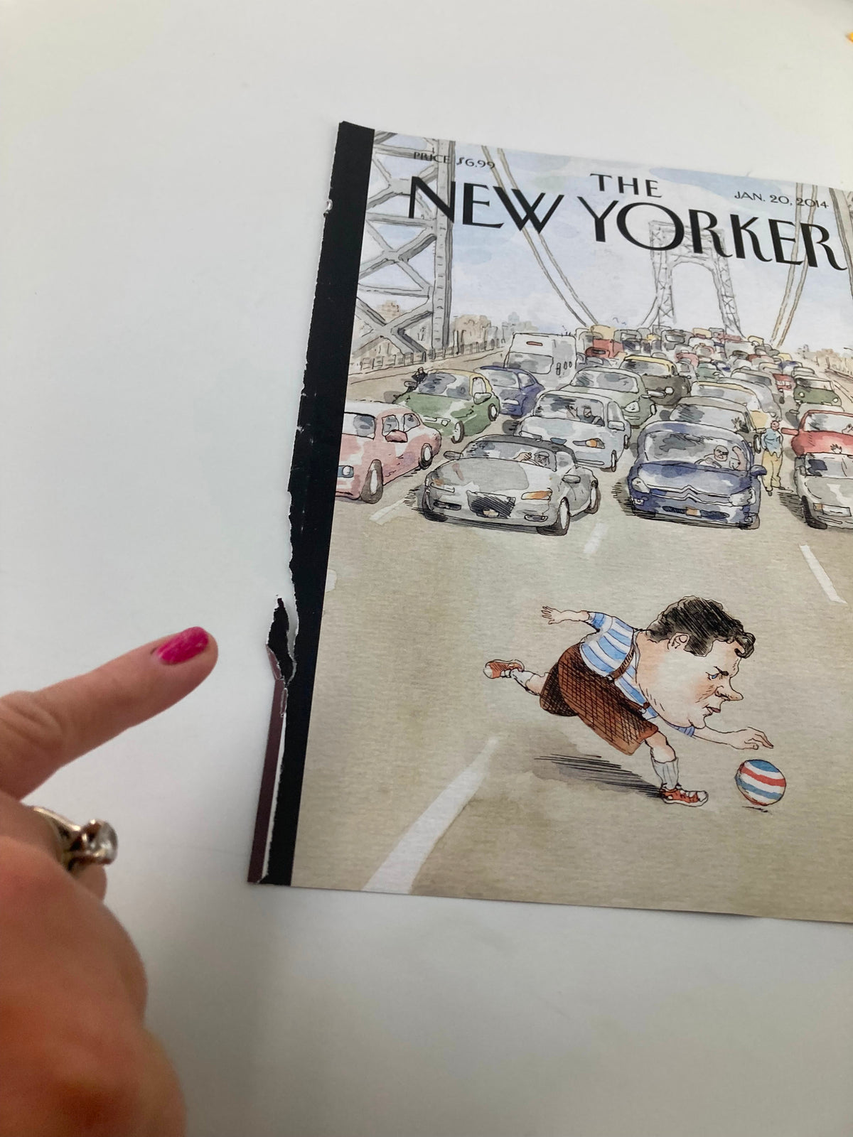 Close-up view of The New Yorker January 20, 2014 cover showing wear on the binding, with a finger pointing to the damaged edge of the vintage magazine.