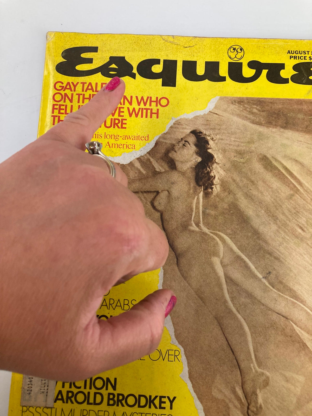Close-up view of the August 1975 VTG Esquire Magazine cover, showing a pink-painted finger pointing at the title 'Gay Talese on the Man Who Fell in Love with This Picture' and 'Sally Quinn: My War with CBS.' This image emphasizes the vintage aesthetic and notable features of the magazine.