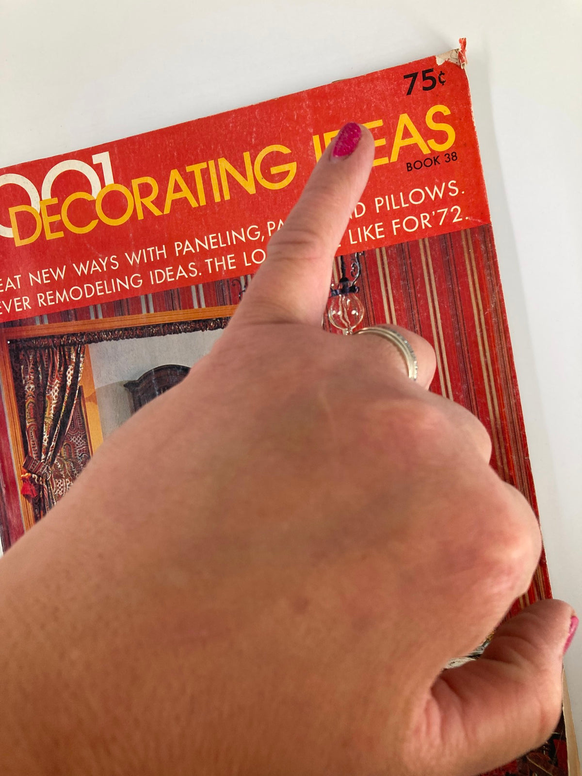 Close-up of the VTG 1001 Decorating Ideas Magazine title from 1971, showcasing the price tag of 75 cents and a finger pointing at the cover, highlighting the vintage design.